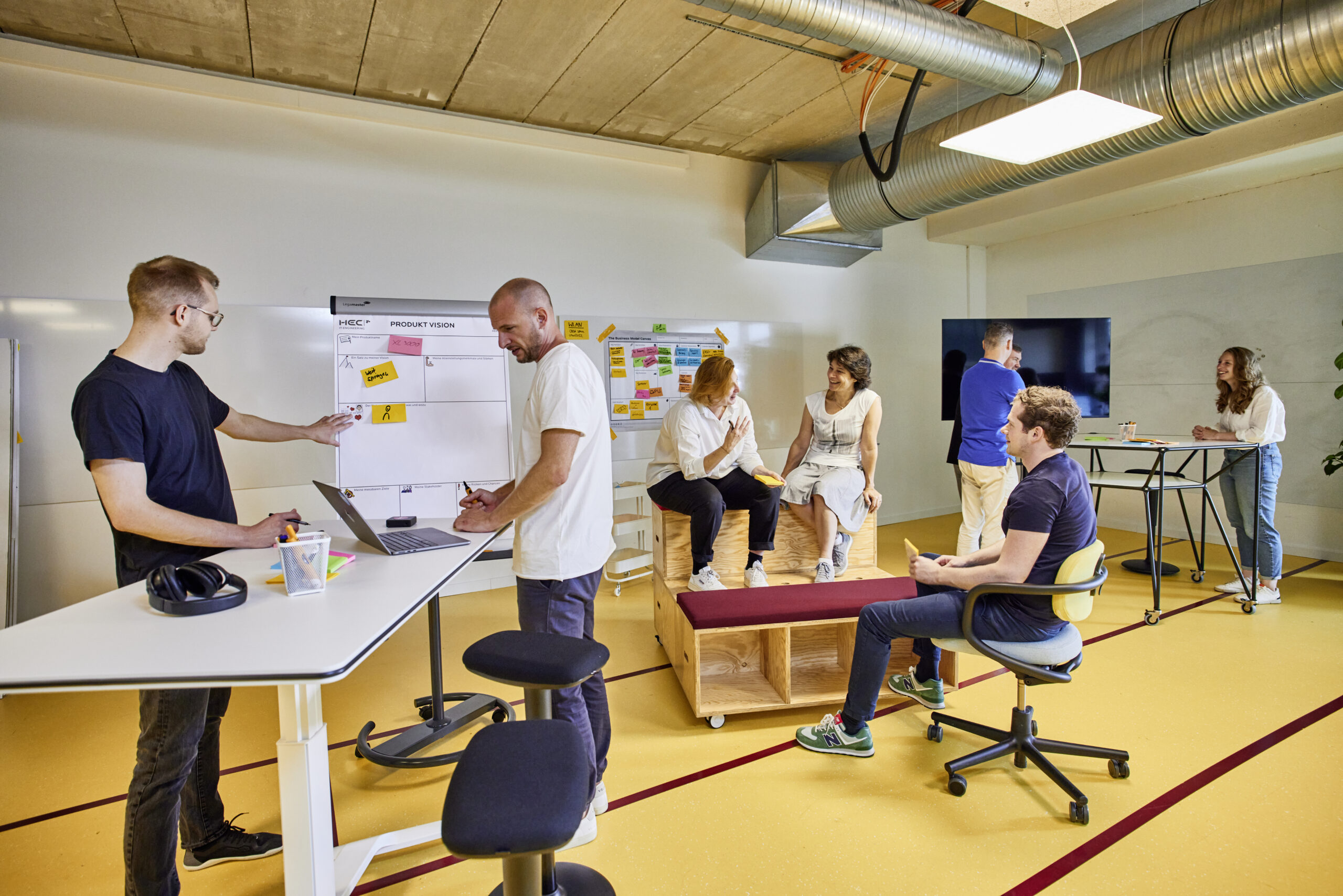 Mehrere kleine Gruppen arbeiten an unterschiedlichen Tischen und unterhalten sich.